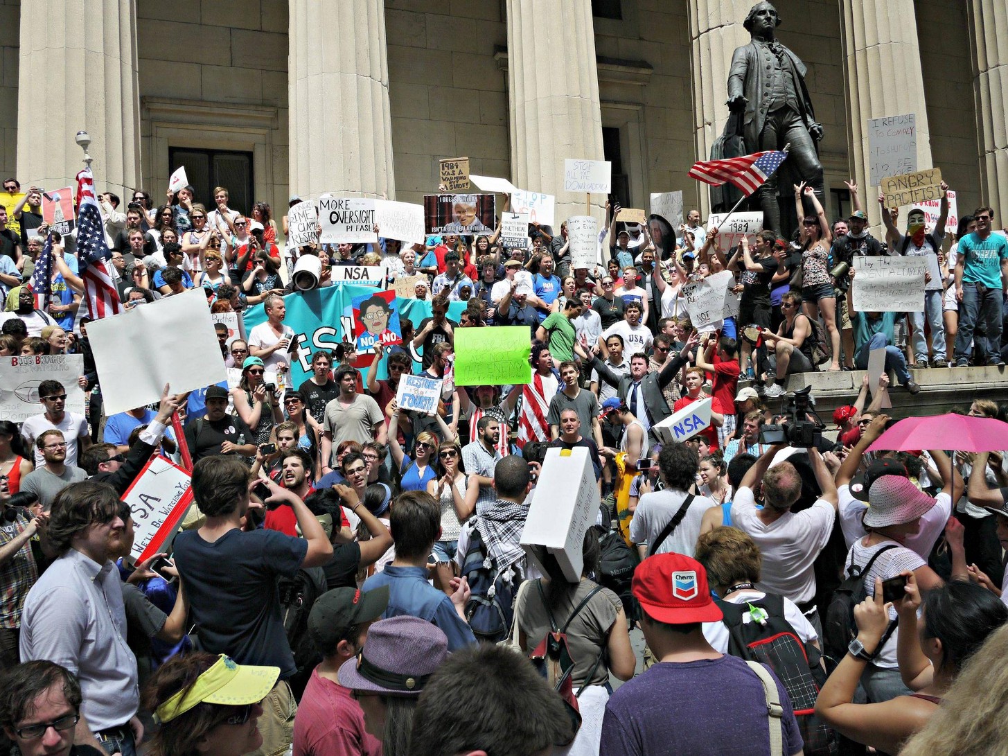 A large growd up people with signs on the steps of an official-looking building